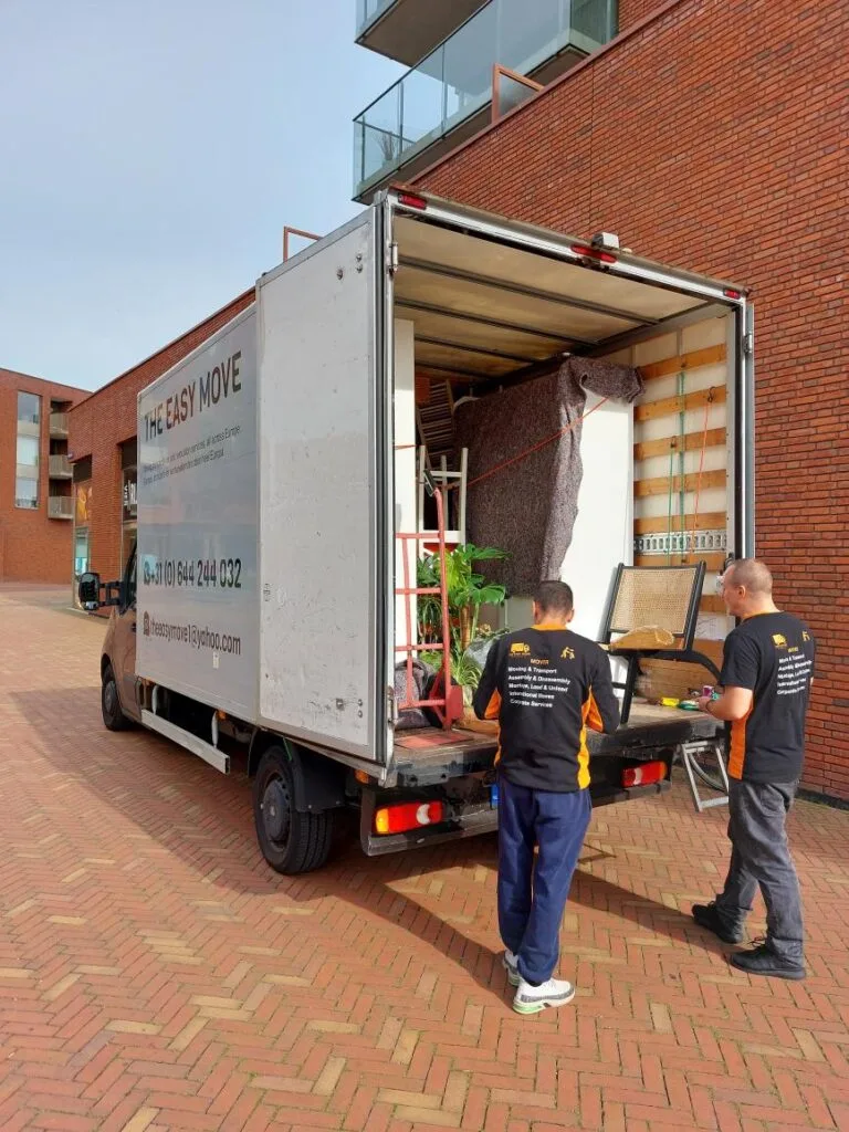 Chauffeur debout à côté d'une camionnette de déménagement à amsterdam, prêt pour un déménagement tout compris
